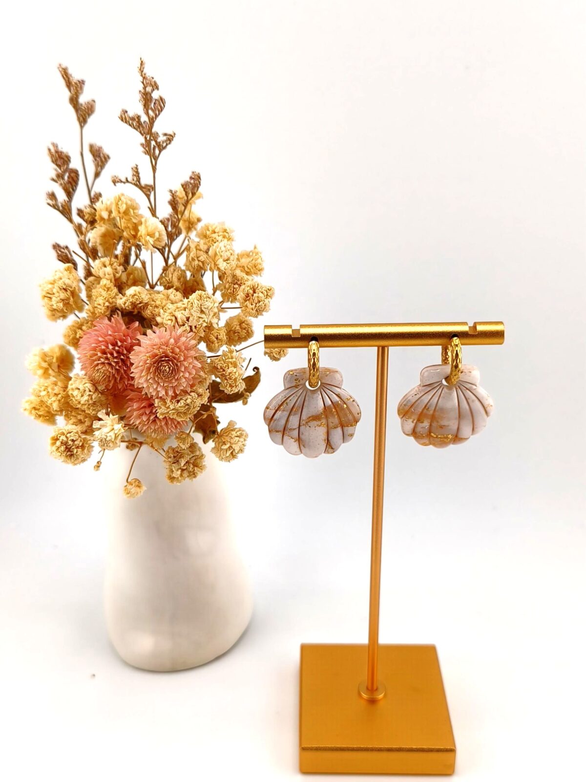 Brincos artesanais em forma de concha do mar, em argila polimérica com efeito mármore bege e dourado, com argolas douradas