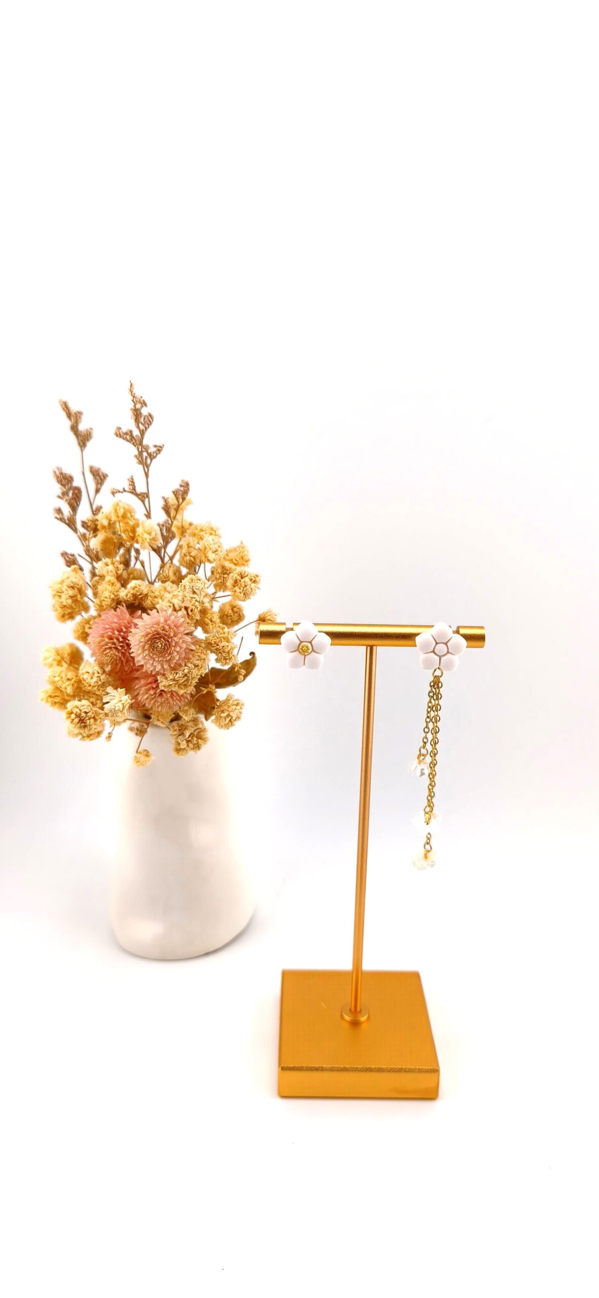 brincos desemparelhados flores brancas dourado alma e vida Brincos desemparelhados com flores brancas e detalhes dourados em expositor